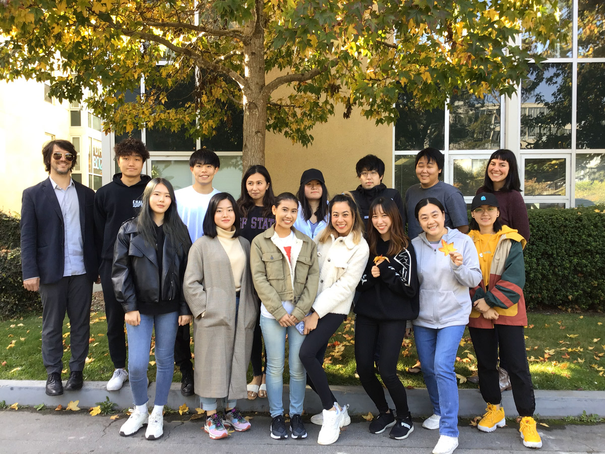 international students stand in a group under a fall tree on campus