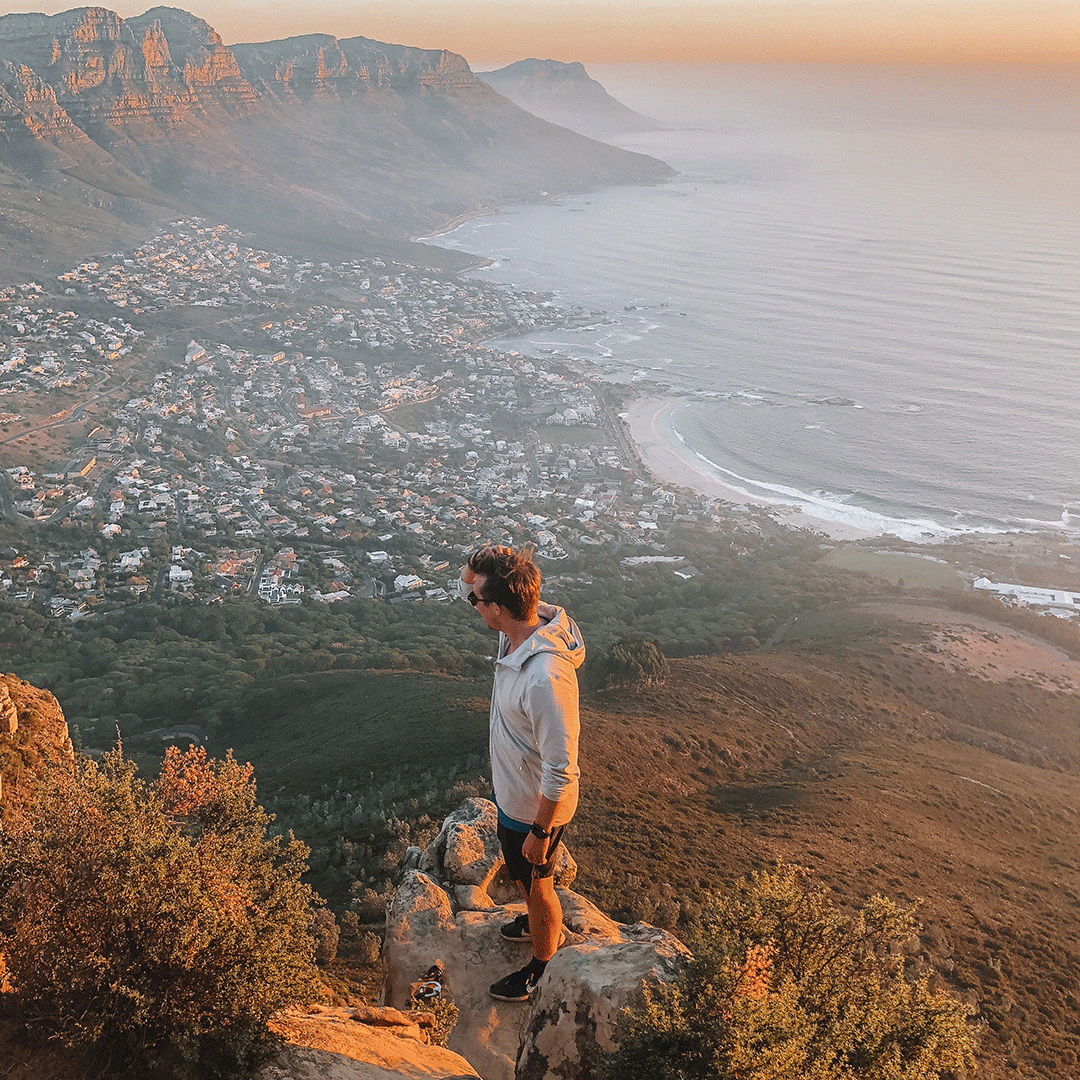 Person on a cliff above Capetown, with a view of the city and the water