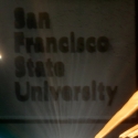 A nighttime view of the SF State sign with streaks of light