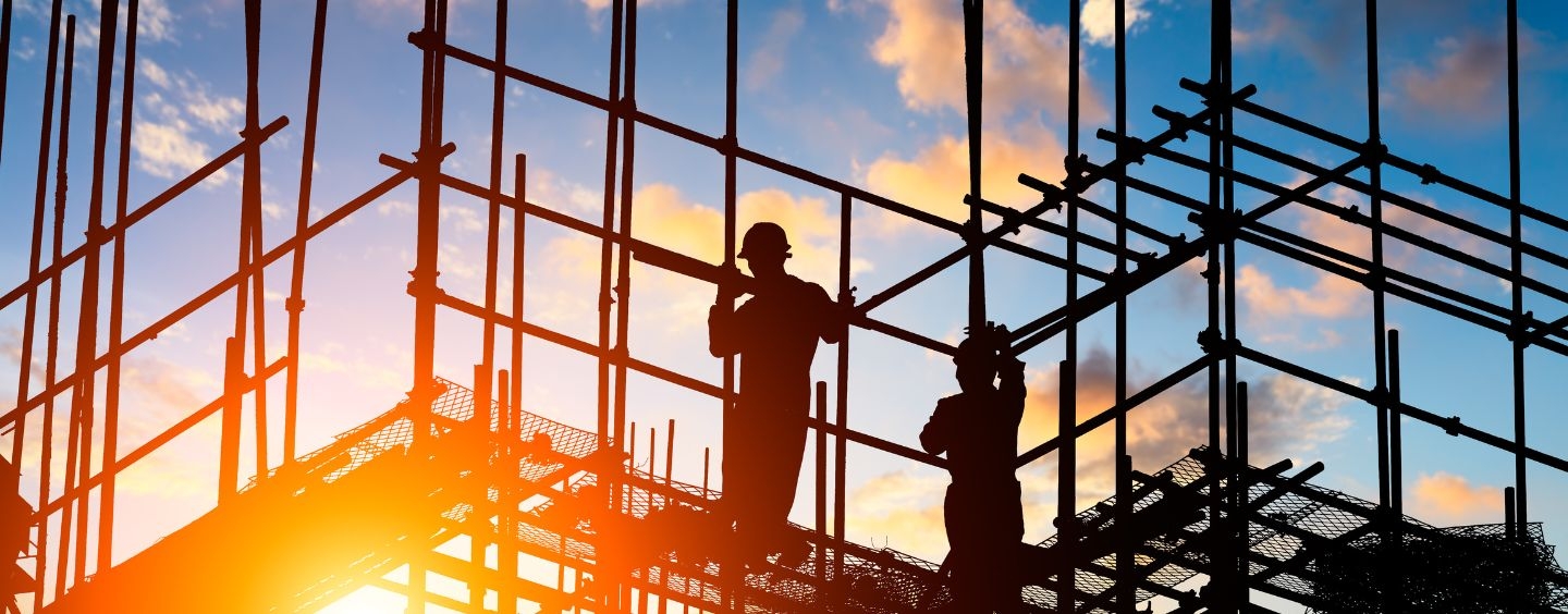 Silhouette of workers and a construction site as the sun sets