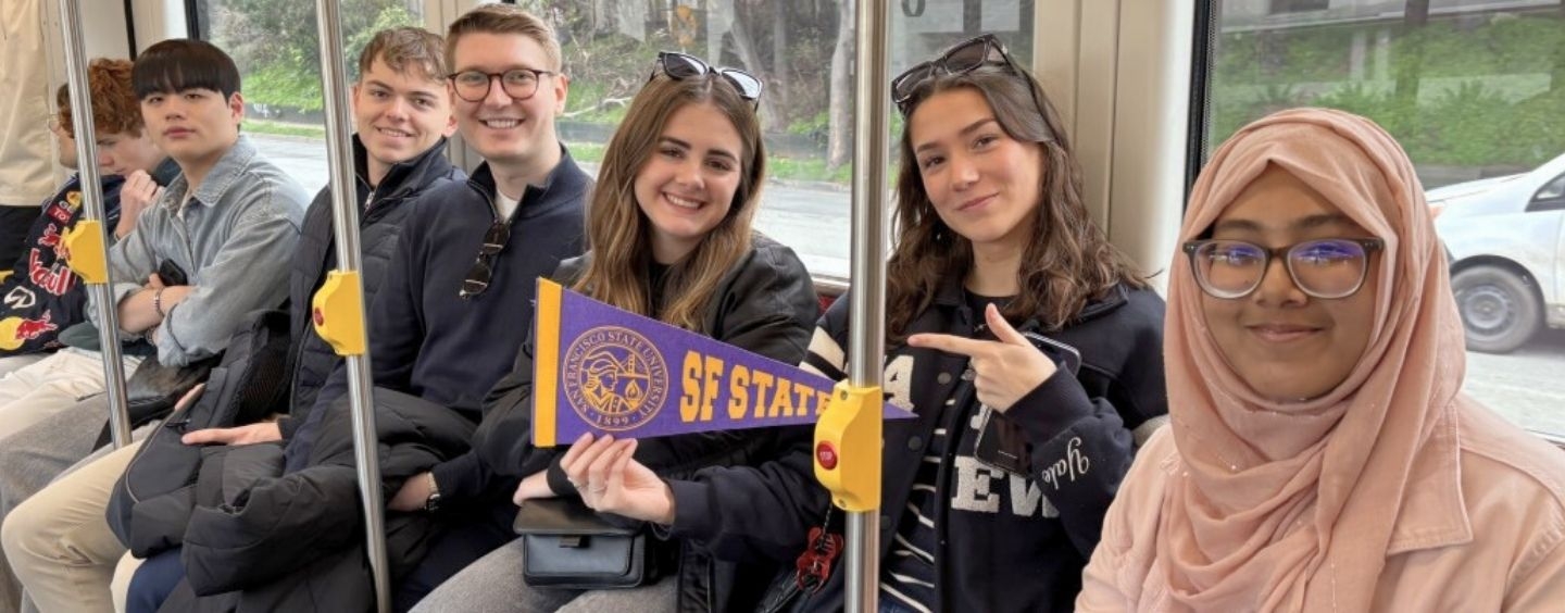 International students on Muni holding an SFSU pennant