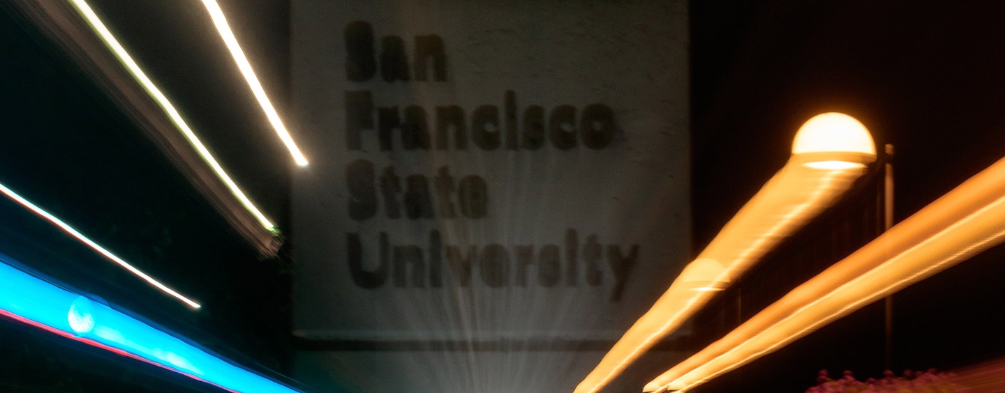 A nighttime view of the SF State sign with streaks of light