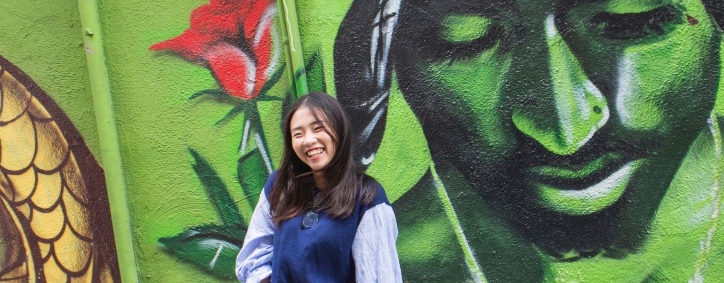 International student poses in front of Tupac mural