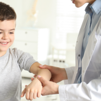 Kid having his arm examined by a school nurse