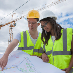 A pair of construction workers examine building plans