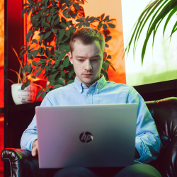 Critical Thinking student studying on his laptop with plants behind him