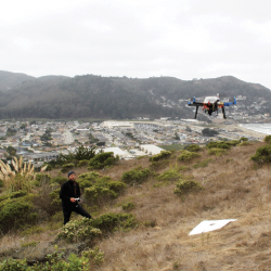 GIS student works with a drone on a hill
