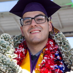 Graduate at Commencement with flower and money leis