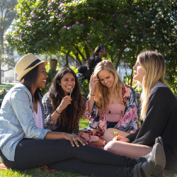 A group of women sit on the SF State campus lawn