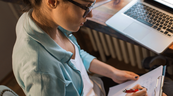 E-Learning instructional designer works on paper and laptop